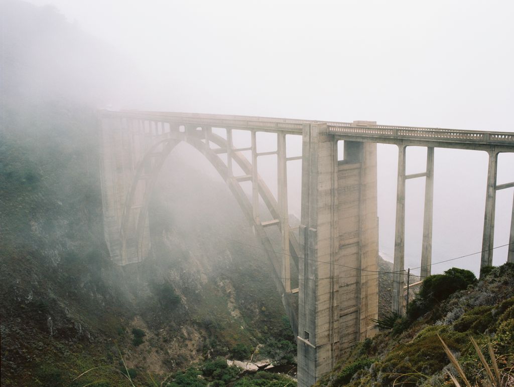 A tall bridge is covered in fog.